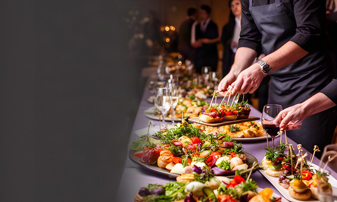Caterer arranging colourful canapés on a long table at an evening event