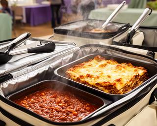 Insulated catering containers holding hot chilli and lasagne ready for a community event